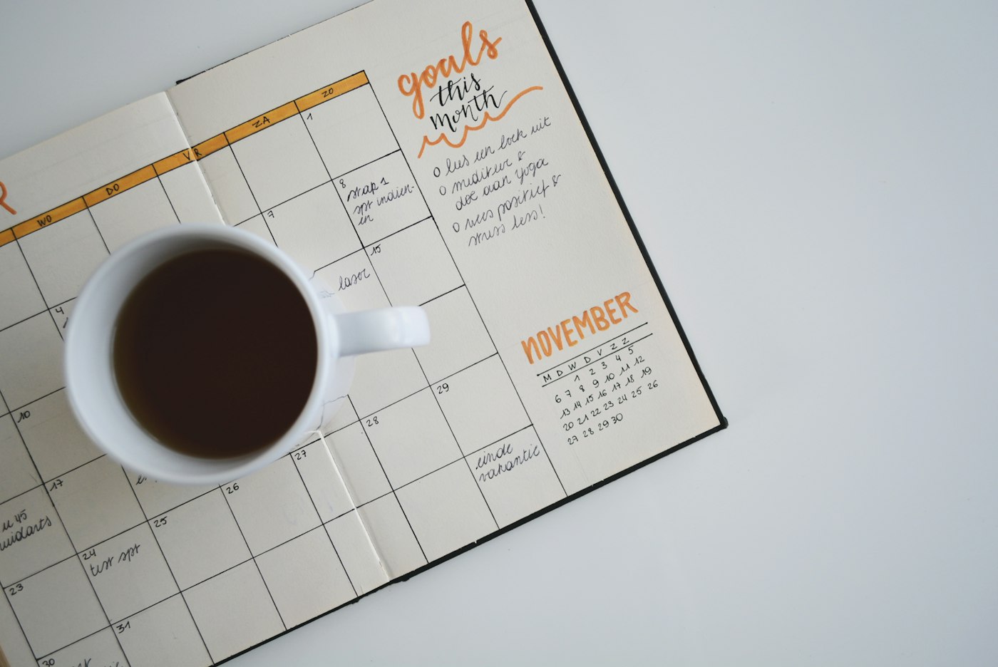 An open paper planner with a cup of coffee, suggesting scheduling and bookings